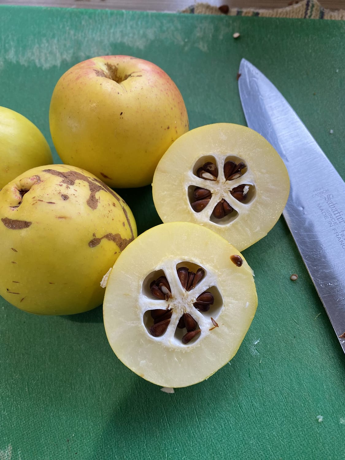 A quince is displayed cut in half on a chopping board showing its interesting core of five pips in a start pattern.