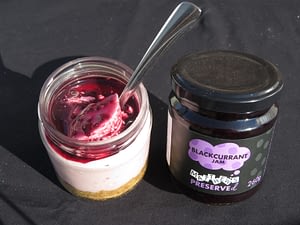 This is a photo of a Blackcurrant Jam Cheesecake made in a jar. The picture shows Matthew's Preserved blackcurrant jam which has been used in the recipe.